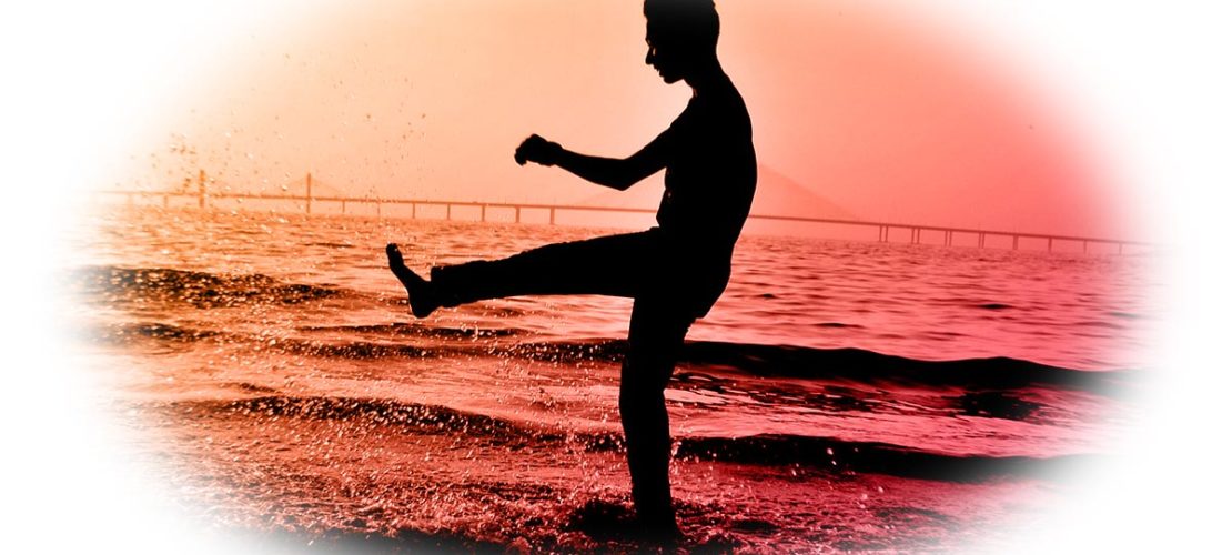 un homme dansant sur la plage à contre-jour